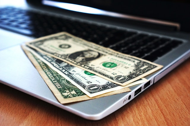 a bunck of banknotes sitting on top of a laptop